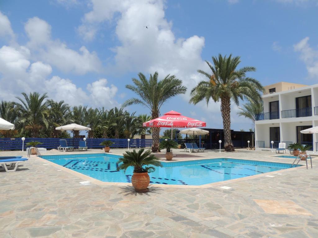 a pool at a resort with palm trees and a building at West End Hotel in Peyia