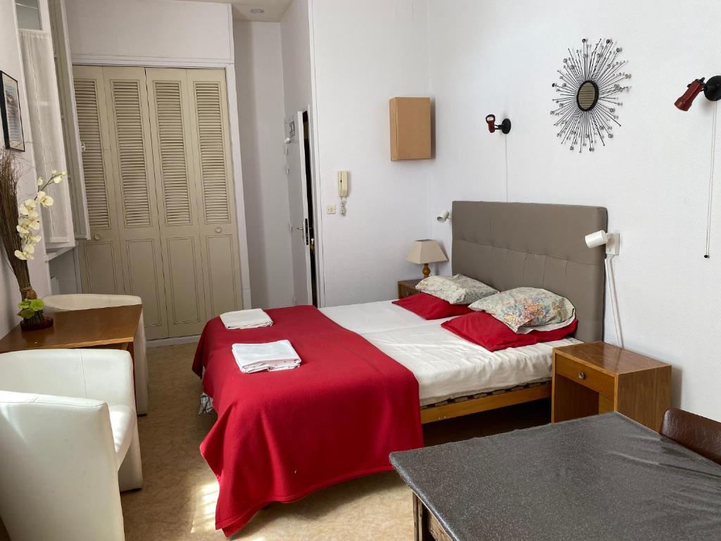 une chambre avec un lit avec une couverture rouge dans l'établissement Logis C12, à Rochefort