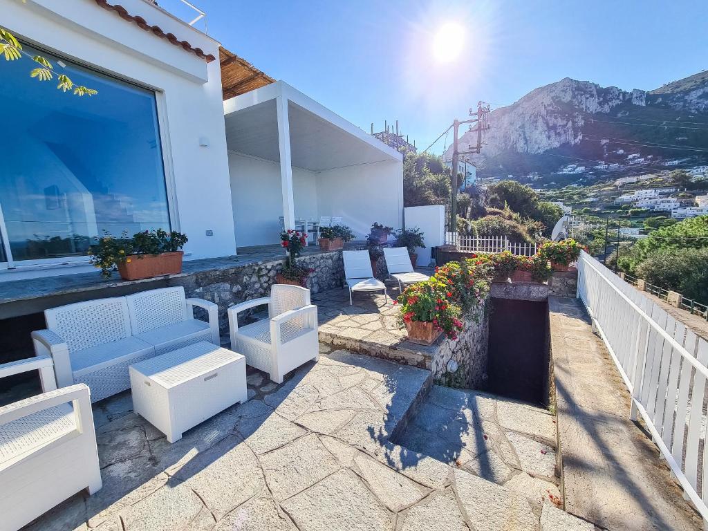 um pátio com cadeiras brancas e mesas numa casa em Casa Capri Me em Capri