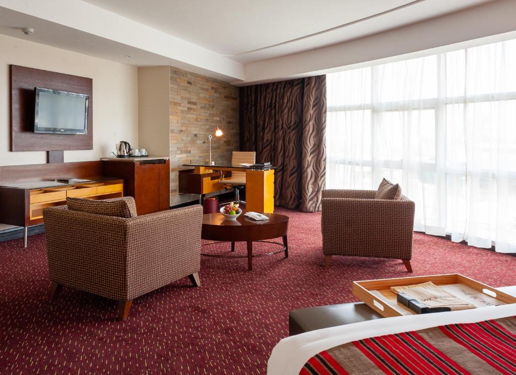 um quarto de hotel com duas cadeiras e uma televisão em The Boma Nairobi em Nairobi