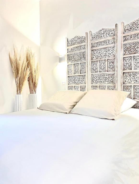 una camera con letto bianco e testiera in legno di L’Escale - Le Boho + garage + NETFLIX a Saint-Étienne