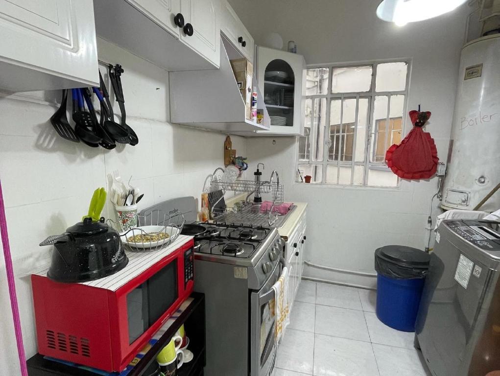 cocina con microondas rojo y fogones en HOSTAL Letys Place Emilio en Ciudad de México