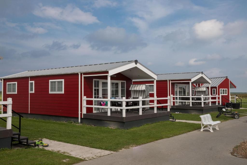 a red house with a porch and a bench in front of it at Ferienhof Schild - Das kleine Bullerbü am Meer in Wangerland