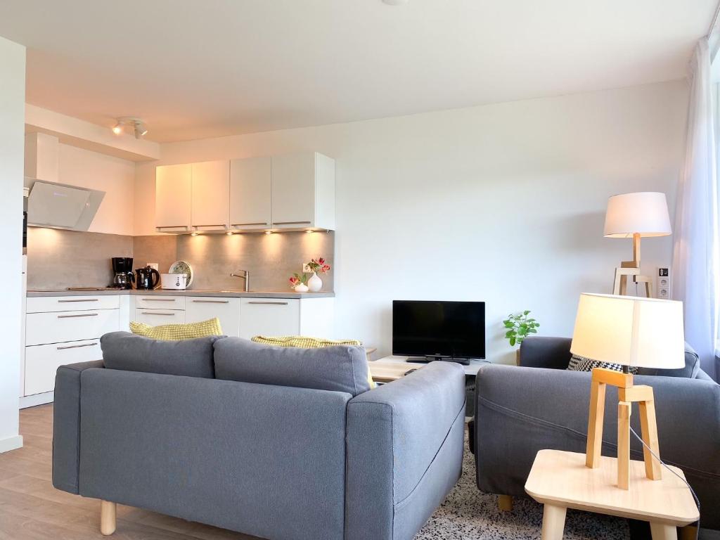 een woonkamer met twee blauwe banken en een keuken bij Vakantieappartement Westkapelle WE07 in Westkapelle