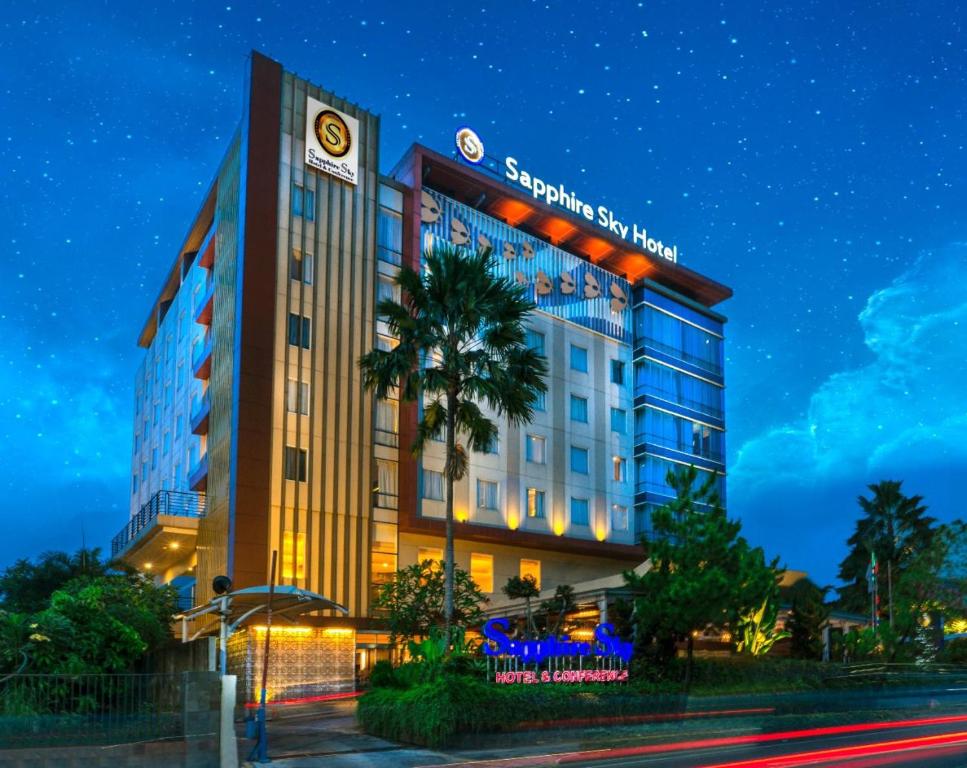 a hotel at night with a palm tree in front of it at Sapphire Sky Hotel & Conference in Serpong