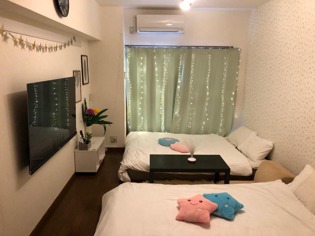 a room with two beds and a green curtain at 駅南うちやまビルさん in Fukuoka