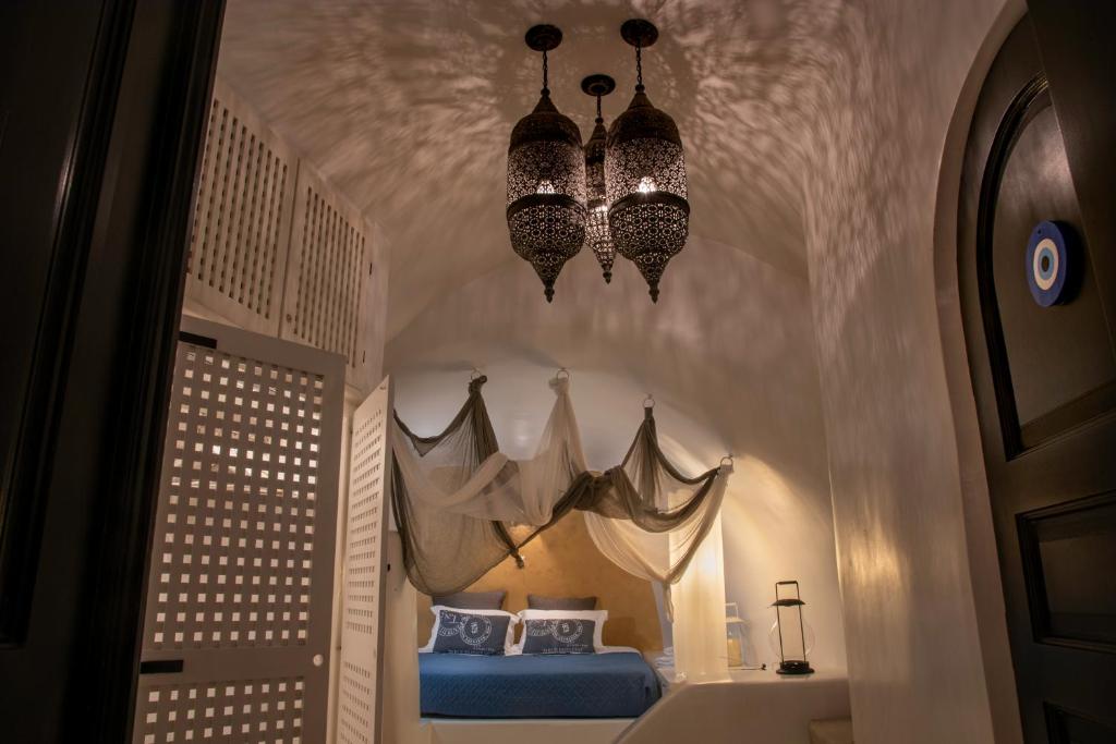 a bedroom with a bed and two chandeliers at Villa Orpheus Santorini in Megalokhori