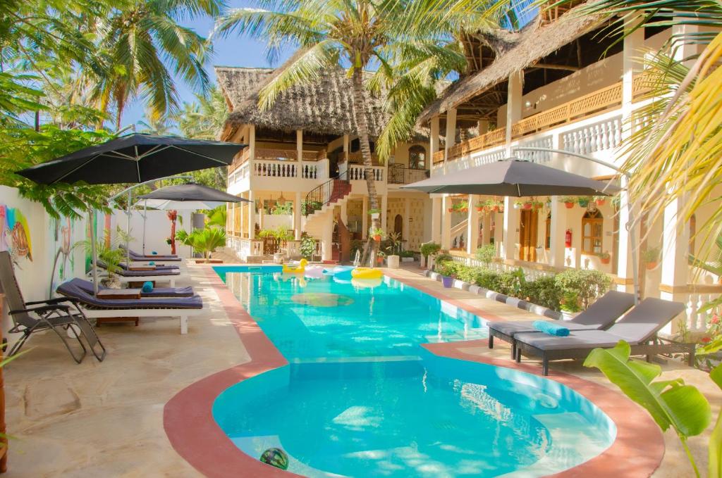 a swimming pool with chairs and umbrellas next to a building at Sunbrella Boutique Hotel in Michamvi