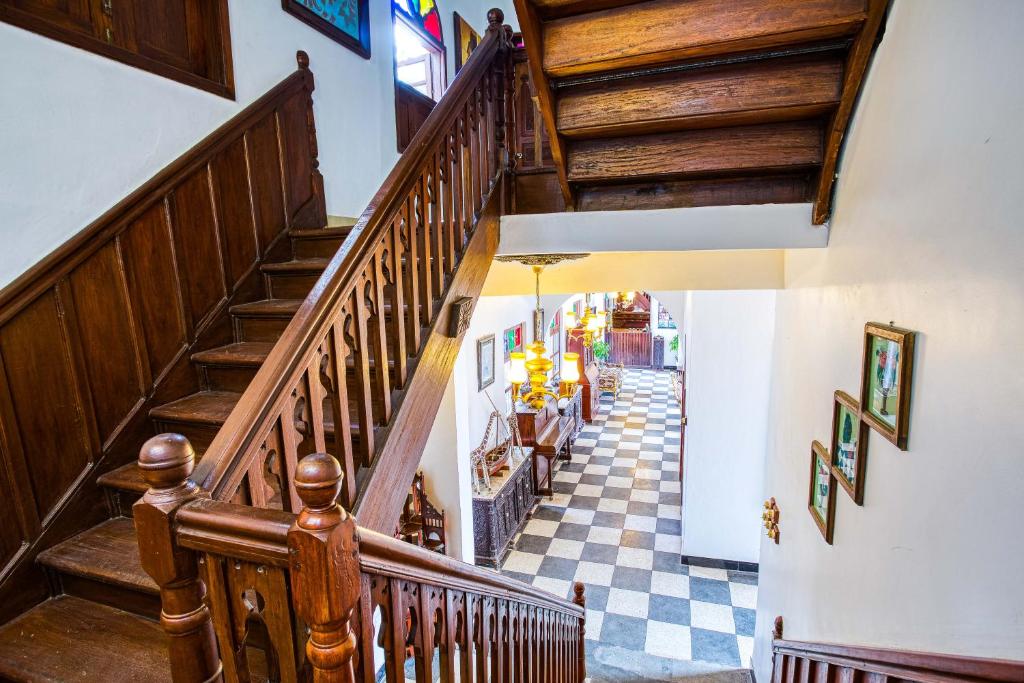 a hallway with wooden stairs and a checkerboard floor at Tembo House Hotel in Zanzibar City