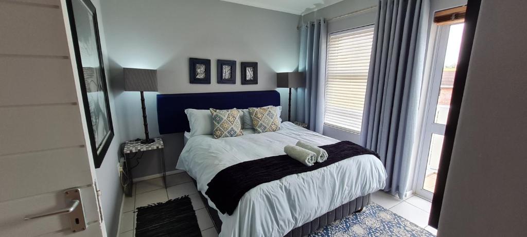 a bedroom with a bed with a blue headboard and a window at Knysna Sunrise @Malachite in Knysna