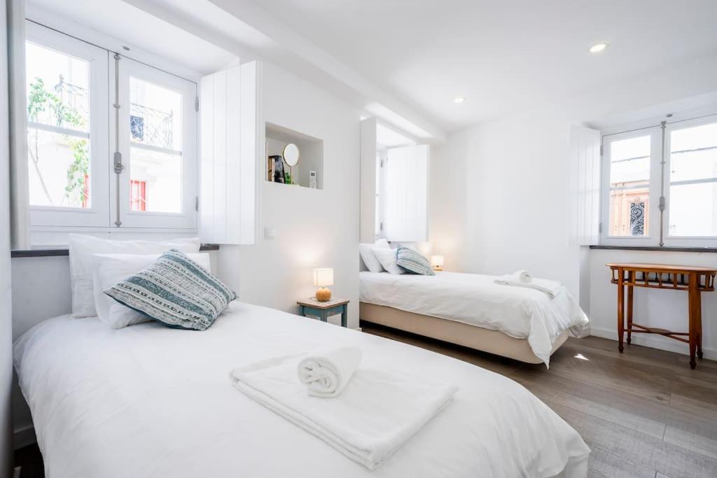 タヴィラにあるPessoa/Rico - Historical Tavira Houseの白いベッドルーム(ベッド2台、窓2つ付)が備わります。