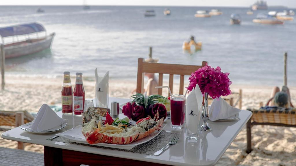 a table with a plate of food on the beach at Tembo House Hotel in Zanzibar City