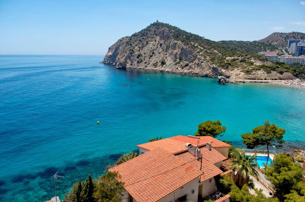 ein Haus mit einem orangenen Dach am Meer in der Unterkunft Aparthotel Ola Blanca in Cala de Finestrat