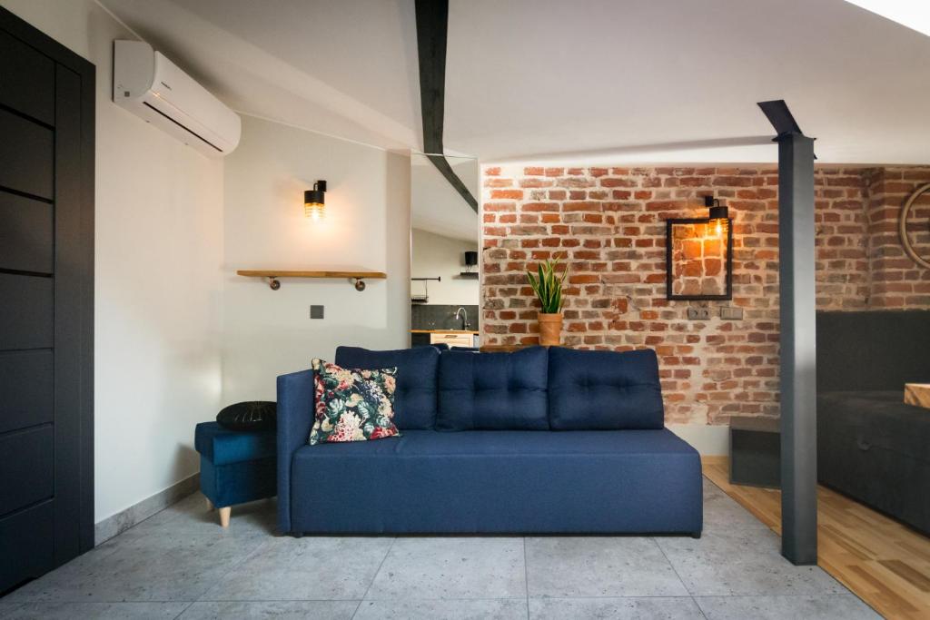 a blue couch in a living room with a brick wall at Apartamenty Fabrykanta Księży Młyn in Łódź