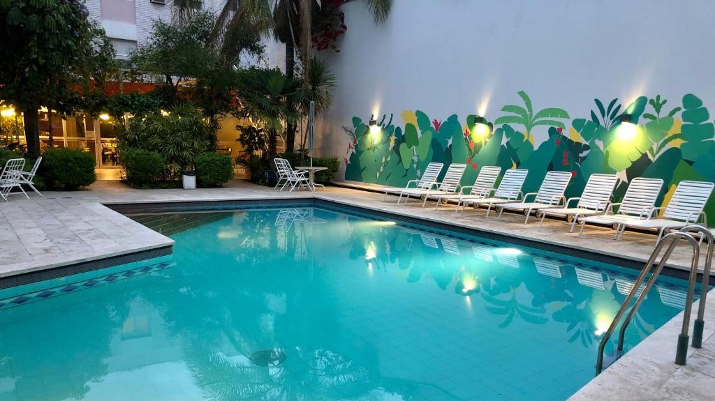 una piscina con sillas y una pared con un mural en Hotel Nutibara en Mendoza