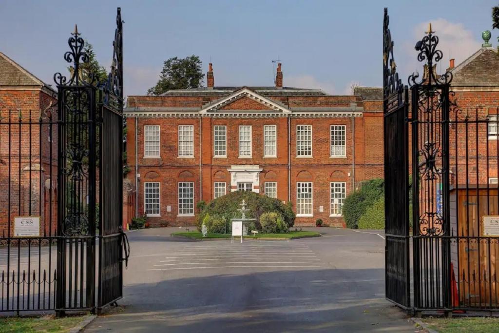 an open gate to a large red brick building at SK Baylis House Hotel in Slough