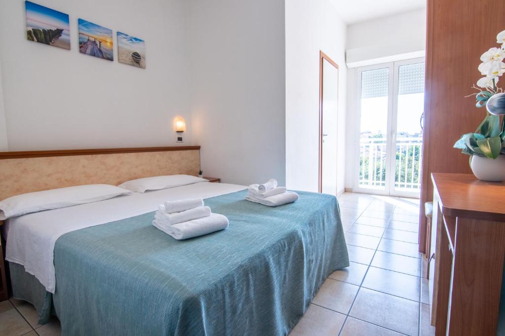 sypialnia z łóżkiem i dwoma ręcznikami na nim w obiekcie HOTEL ADRIA BEACH w Rimini