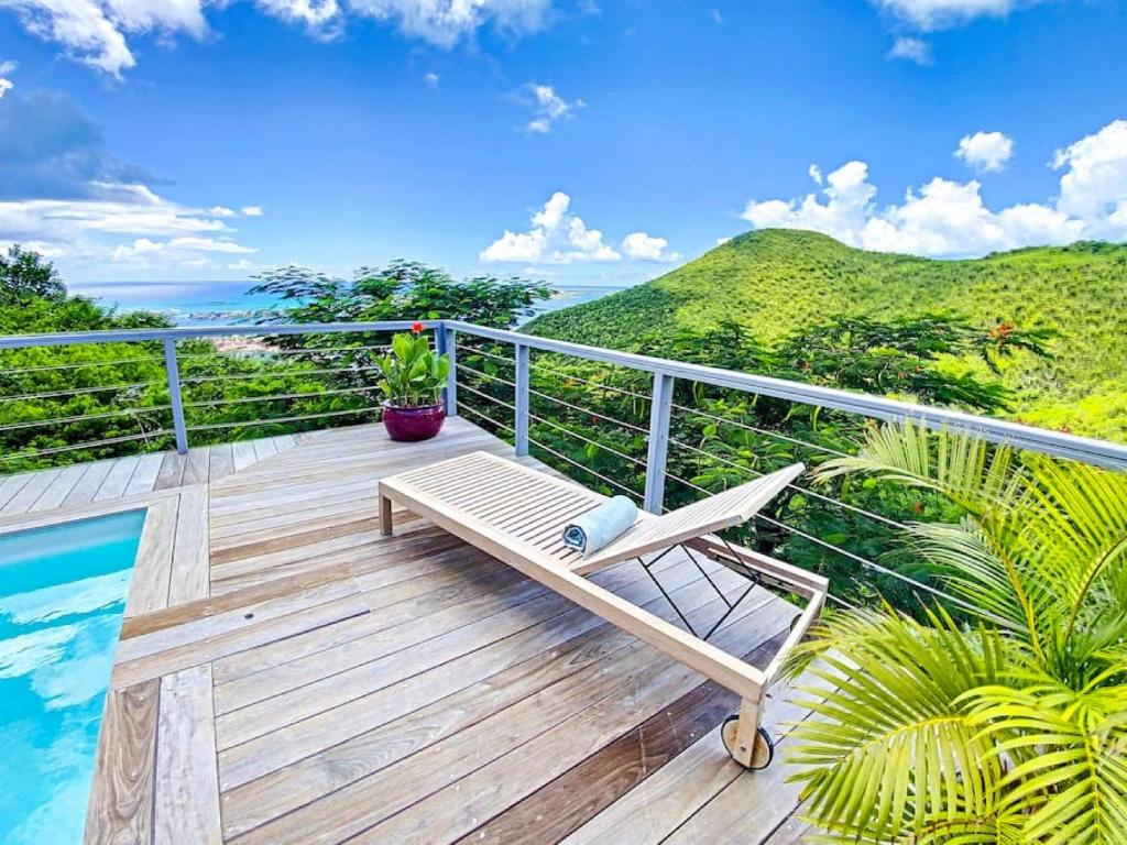 a deck with a bench and the view of the ocean at Aquamarine, private room in Villa Casa Blue pool sea view in Koolbaai