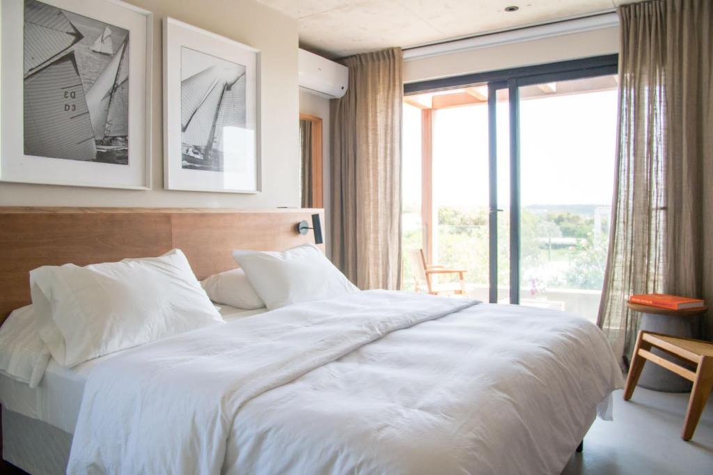 a bedroom with a white bed and a large window at Casa Tilo in José Ignacio
