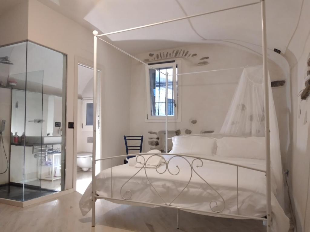 Schlafzimmer mit einem weißen Bett und einem Spiegel in der Unterkunft Casa Roberta in Dolceacqua
