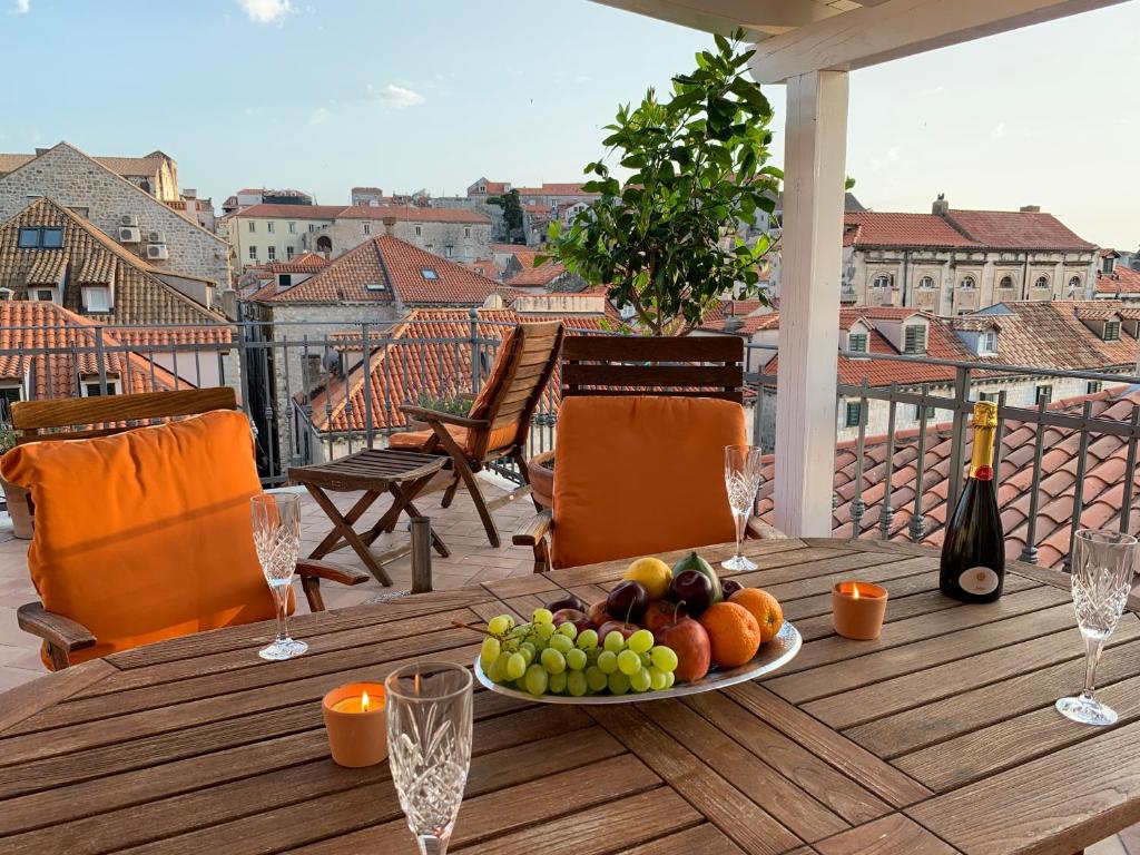 un plato de fruta en una mesa de madera en un balcón en LOCUS Dubrovnik, en Dubrovnik