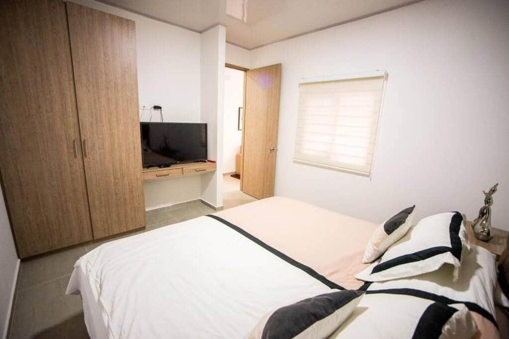 sypialnia z białym łóżkiem i telewizorem w obiekcie 206-INCREIBLE APARTA ESTUDIO EN GRanada w mieście Cali