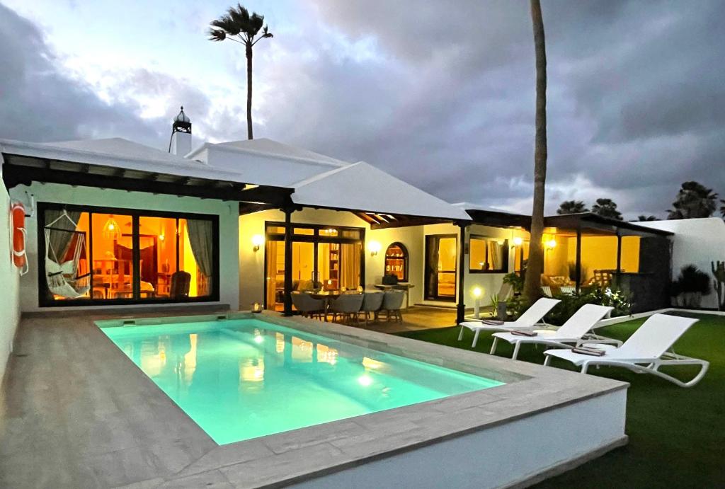 a villa with a swimming pool in front of a house at Villa Vista del Mar - Oceanfront Luxury with Private Pool in Costa Teguise