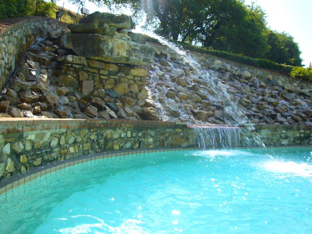 a swimming pool with a waterfall in the background at Mulino Di Quercegrossa in Quercegrossa