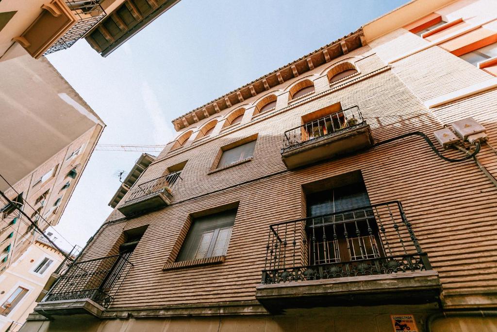 un grand bâtiment en briques avec des fenêtres et des balcons dans l'établissement Capricho de Vidania, à Huesca