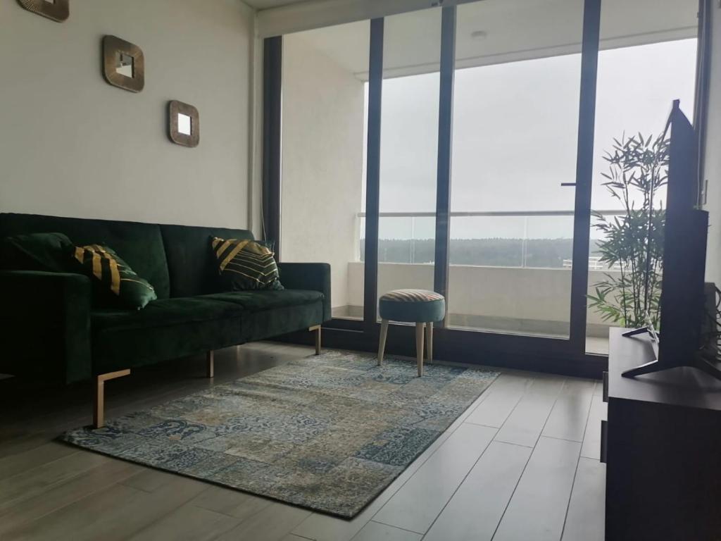 a living room with a green couch and large windows at Reñaca - Eluchans Plaza in Viña del Mar