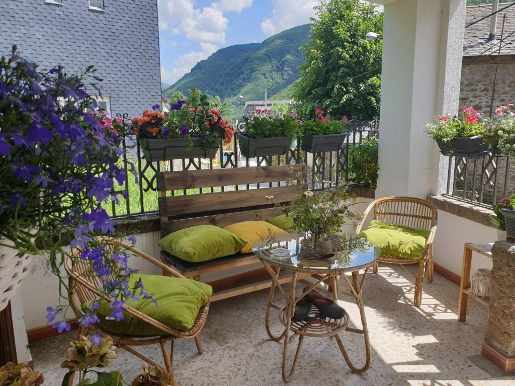 - un balcon avec un banc, une table et des fleurs dans l'établissement Villa Sabina "Vivienda de Uso Turístico", à Caboalles de Abajo