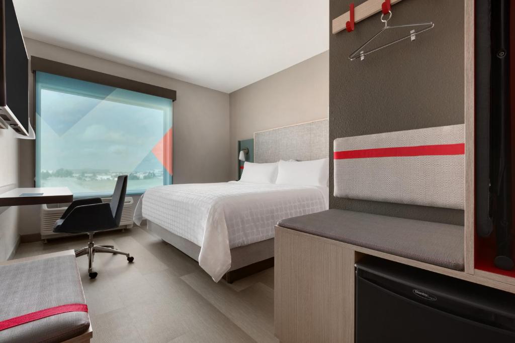 ein Hotelzimmer mit einem Bett, einem Schreibtisch und einem Fenster in der Unterkunft avid hotels - Memphis - Southaven, an IHG Hotel in Southaven