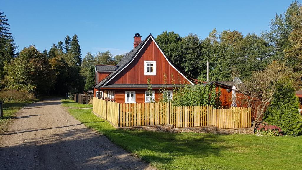 een rood huis met een hek naast een weg bij Chalupa u lesa in Červená Voda