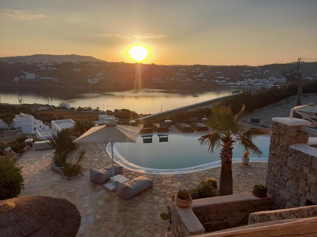 a sunset over a swimming pool on top of a house at Navy Blue Suites in Ornos