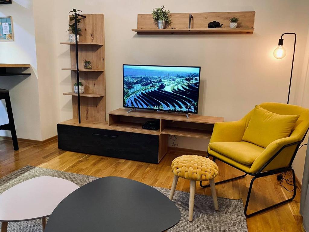 un salon avec une télévision et une chaise jaune dans l'établissement NEWTOWN APARTMENT, à Nikšić
