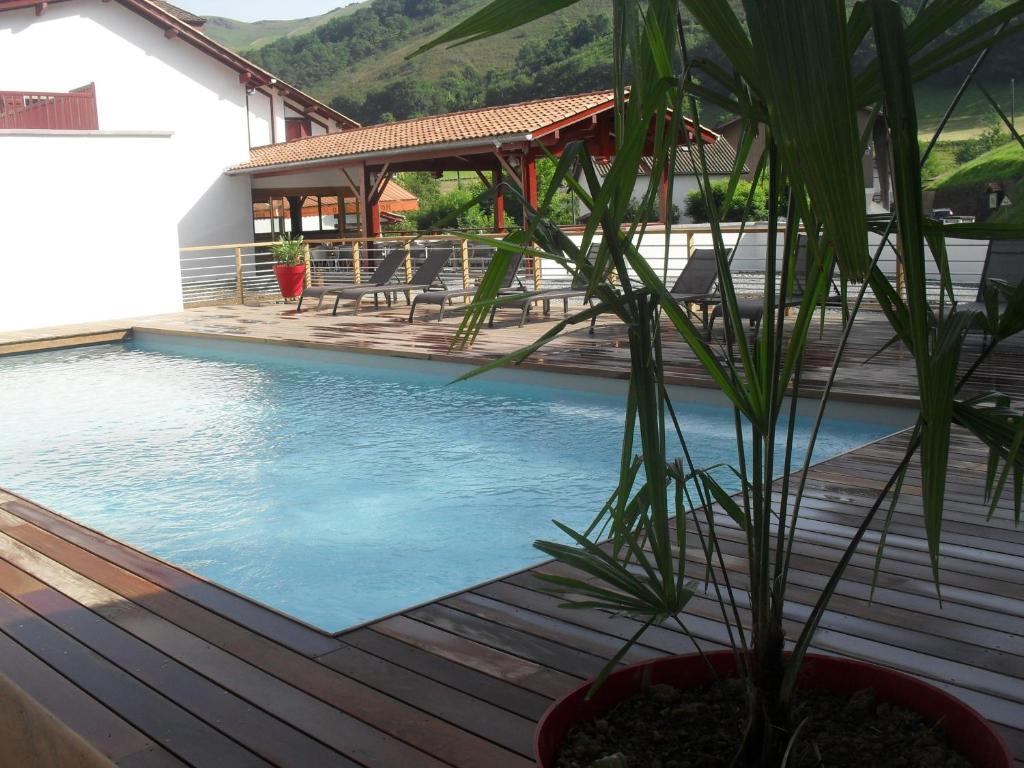 una maceta sentada en una terraza junto a una piscina en Logis Hôtel Andreinia & Cabanes, en Esterençuby