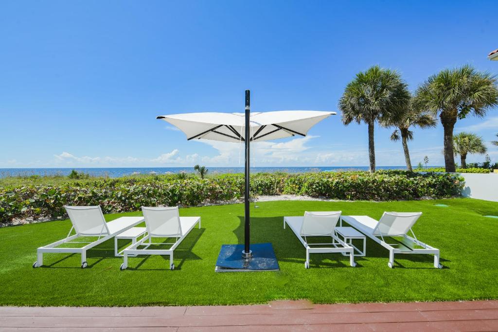 a group of white chairs and an umbrella at Casey Key Resorts - Beachfront in Venice