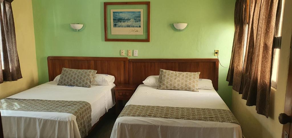 two beds in a room with green walls at Hotel El Faro Malecon in Veracruz
