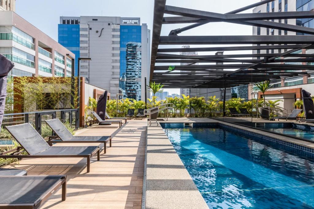una piscina con sedie a sdraio accanto a un edificio di Charlie NUN Itaim a San Paolo