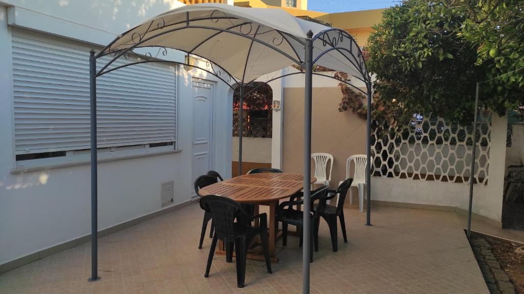 une table et des chaises en bois sous un parasol dans l'établissement Casa Branca, à Armação de Pêra