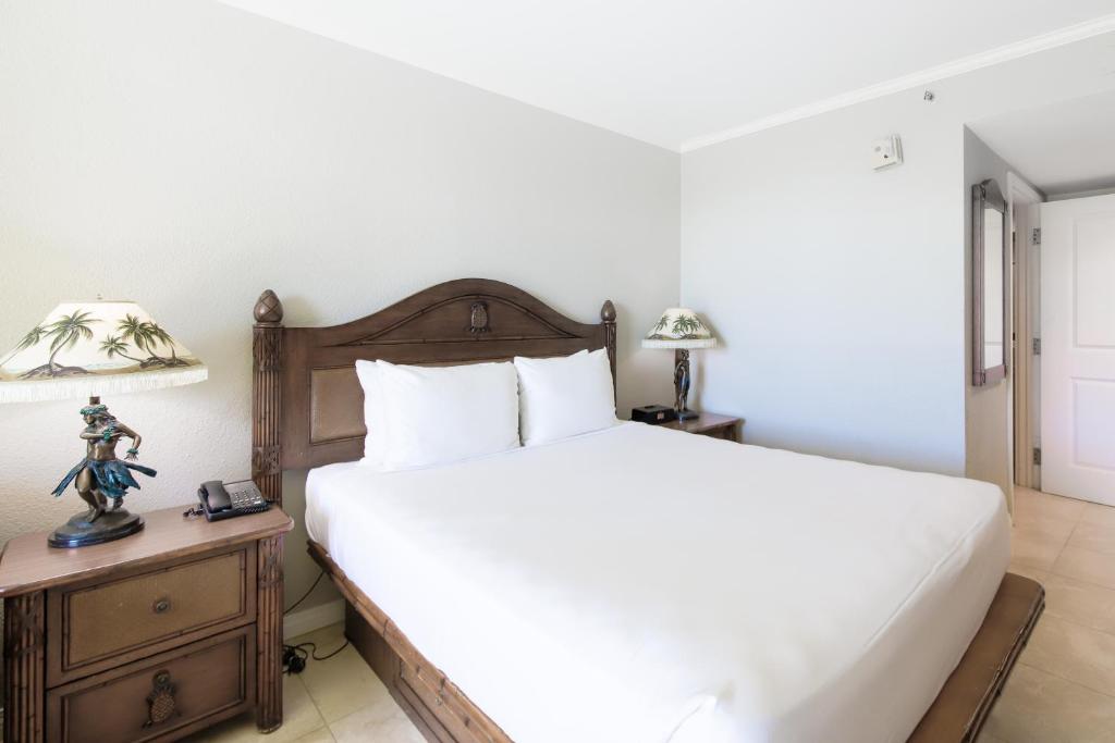 a bedroom with a large bed and a night stand with a lamp at Luana Waikiki #710 in Honolulu