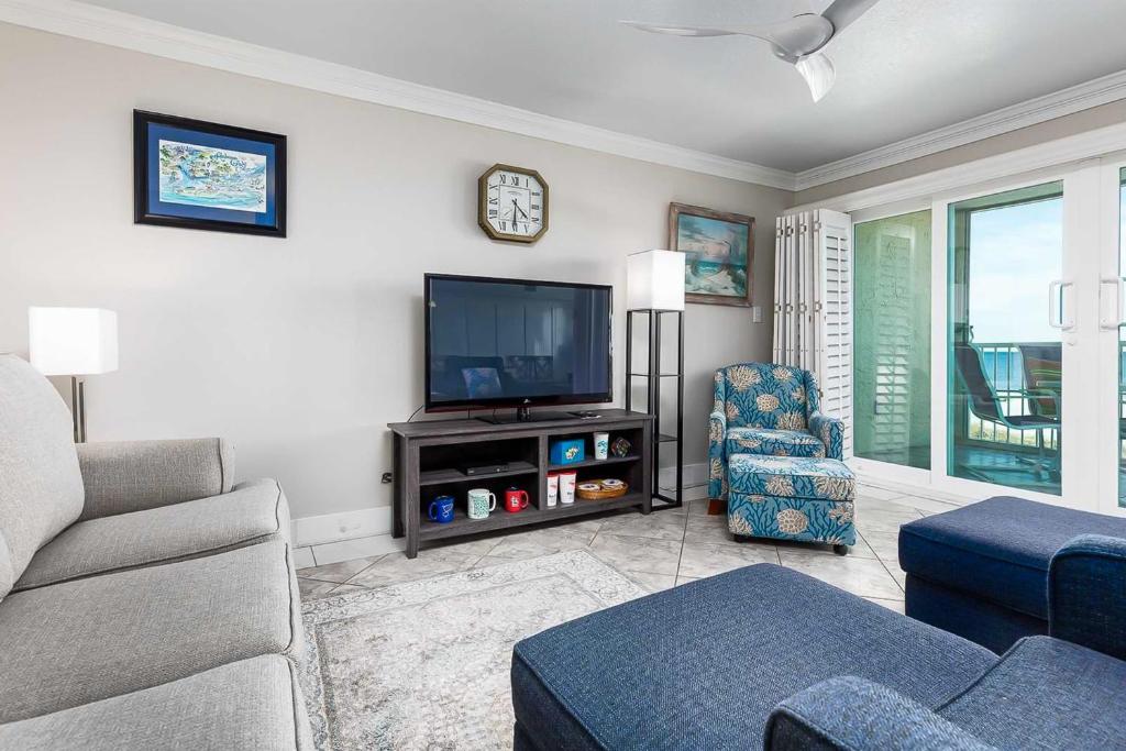 een woonkamer met een tv en een bank en een stoel bij The Castaways in Gulf Shores