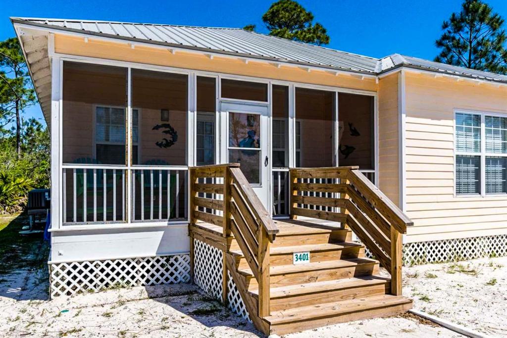 uma pequena casa com um alpendre e uma escada de madeira em Down the Shore em Gulf Shores