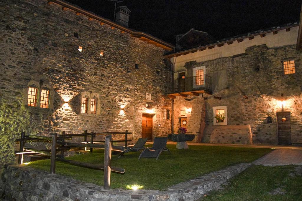 a stone building with two chairs in front of it at night at Povillus - Dimora Medievale in Quart