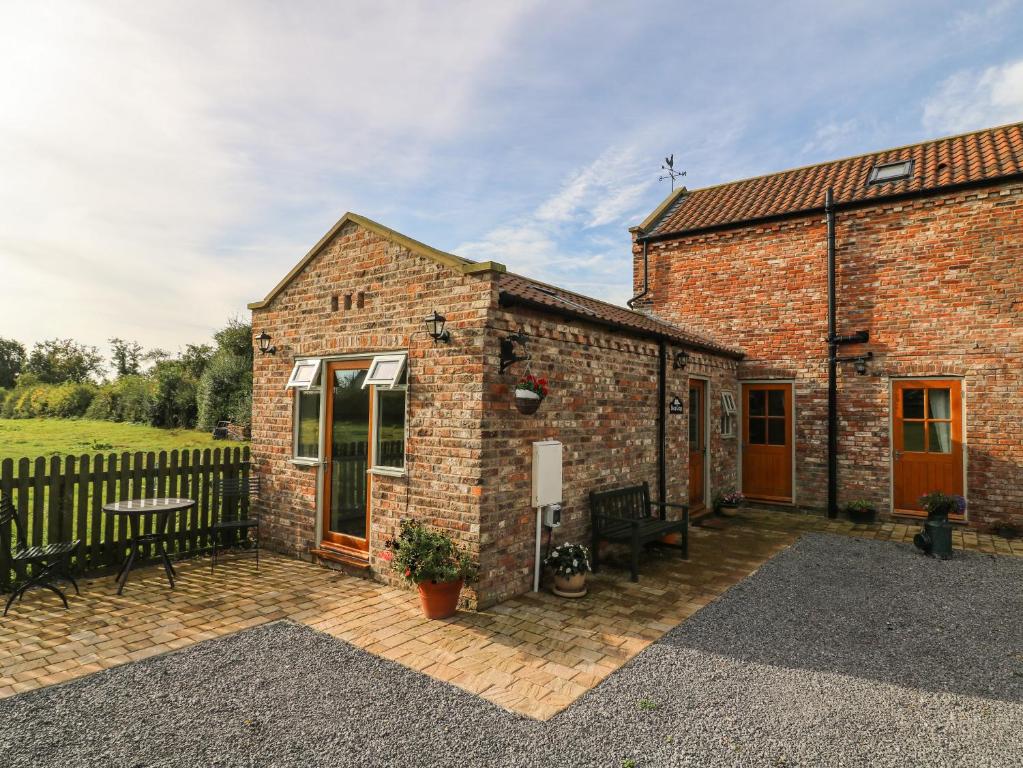 a brick building with a bench on a patio at Decca Cottage Nidd Grange in York