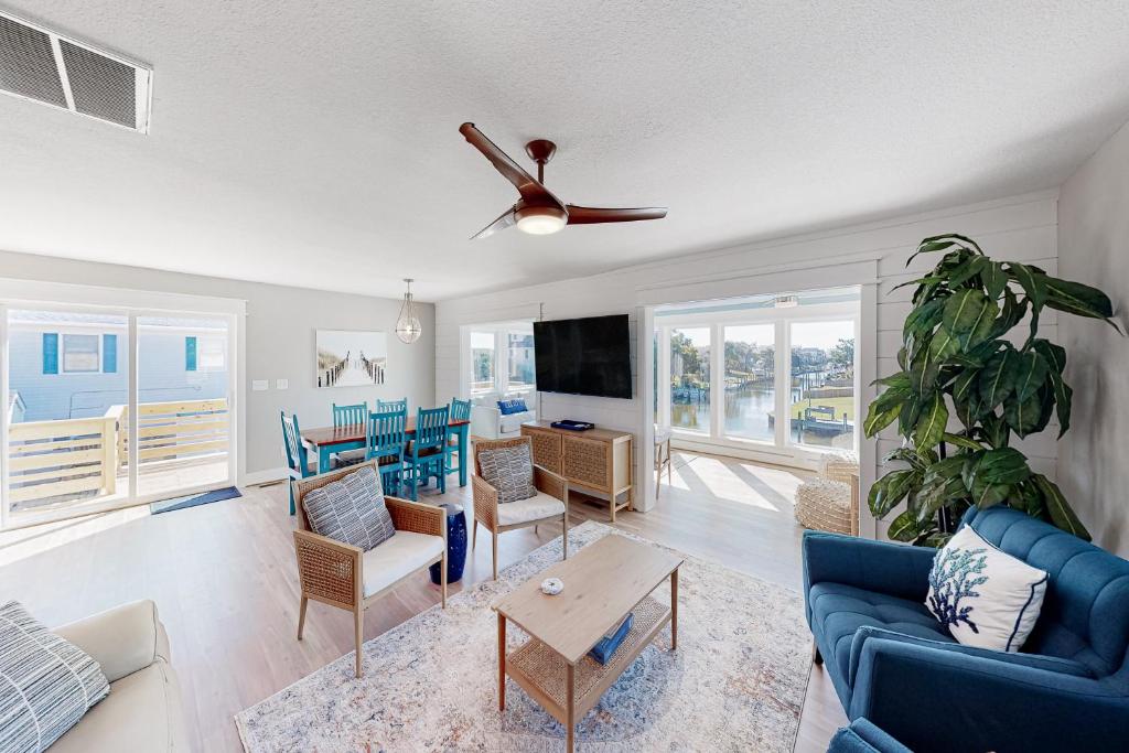 uma sala de estar com um sofá azul e uma ventoinha de tecto em Island Trader 103 em Nags Head