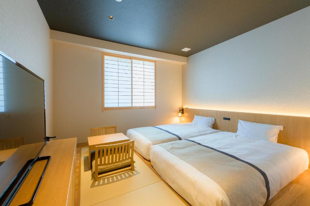 a bedroom with a large white bed and a desk at Tosei Hotel Cocone Kamakura in Kamakura