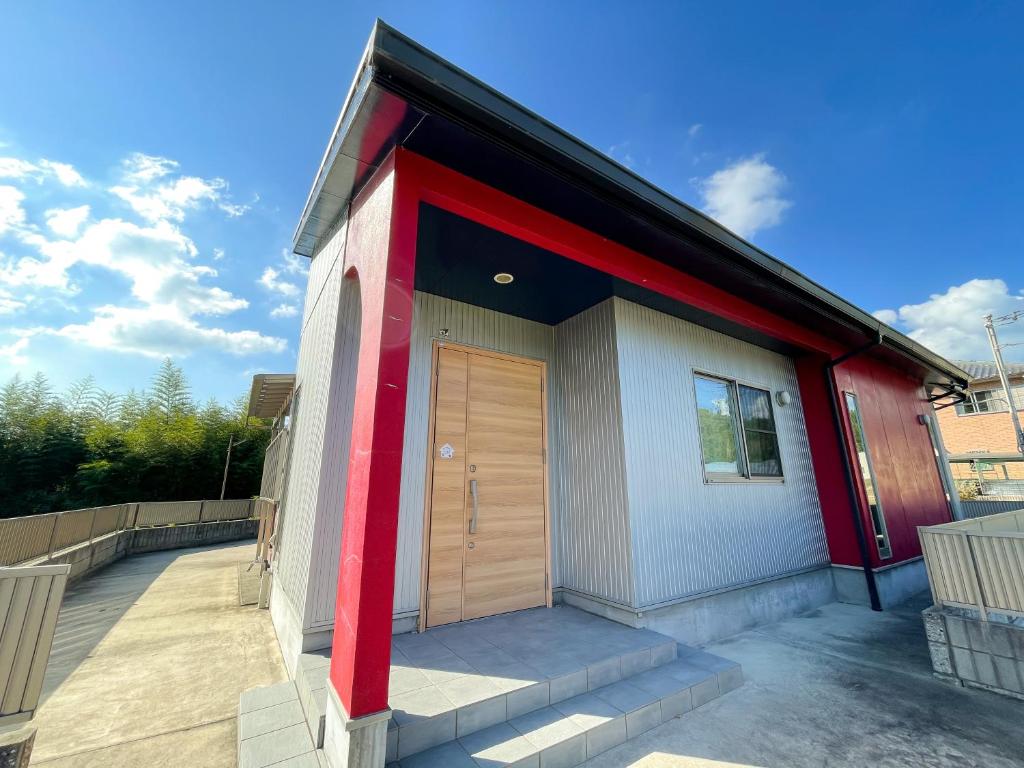czerwono-biały budynek z drewnianymi drzwiami w obiekcie Tiz wan 中田あわじ w mieście Awaji