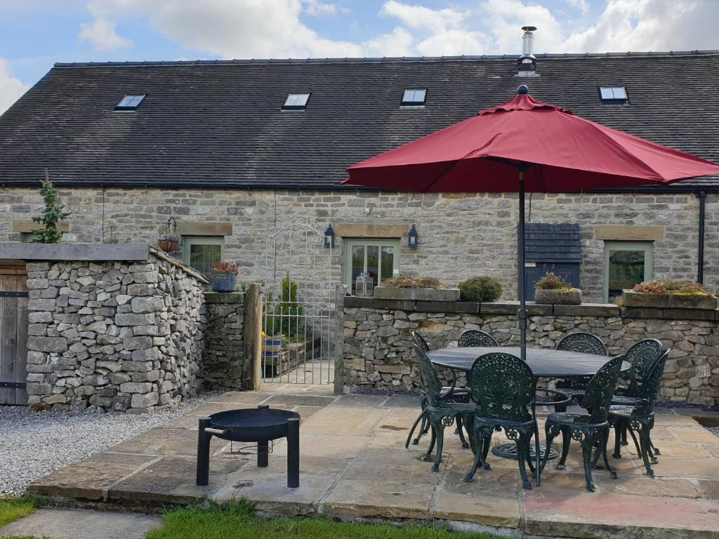 a table and chairs with an umbrella in front of a building at Spingle Barn in Monyash