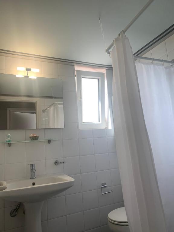 łazienka z umywalką, toaletą i oknem w obiekcie Christopher's Apartments w mieście Skála Kefalonias